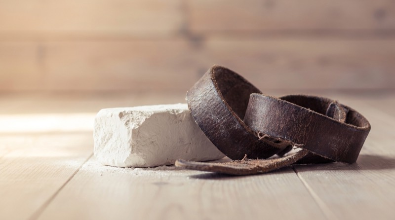 A generated still life, not a photograph of this business: a block of lifting chalk and worn leather straps on floorboards.